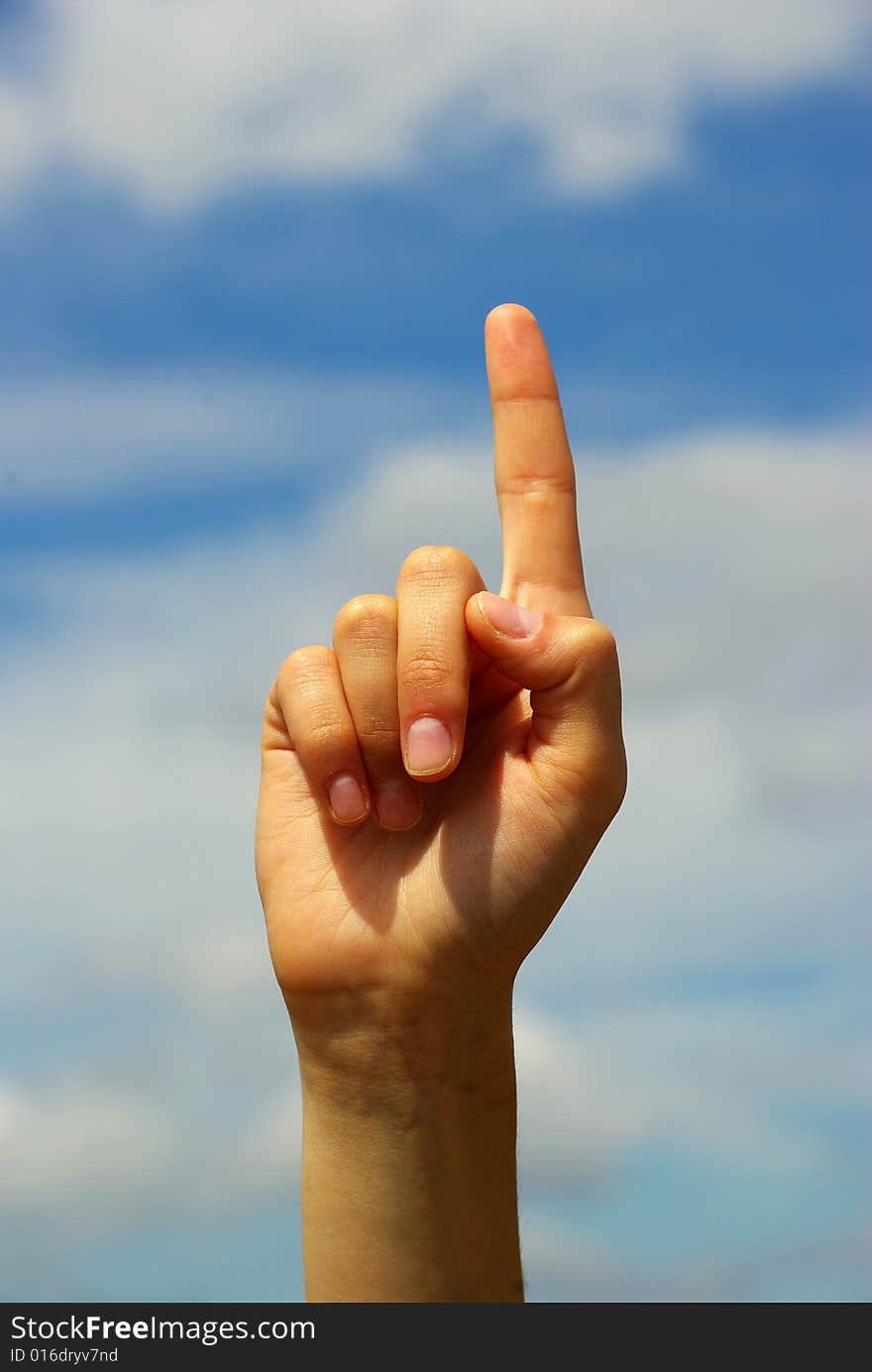 Hand pointing with index finger against a sky background