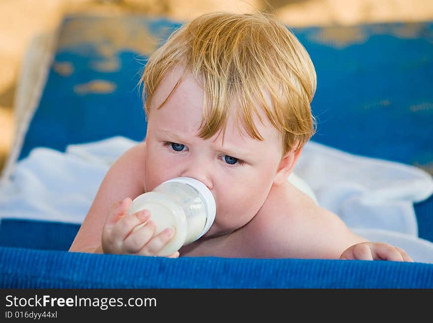 Thoughtful child lays and drinks milk from a bottle