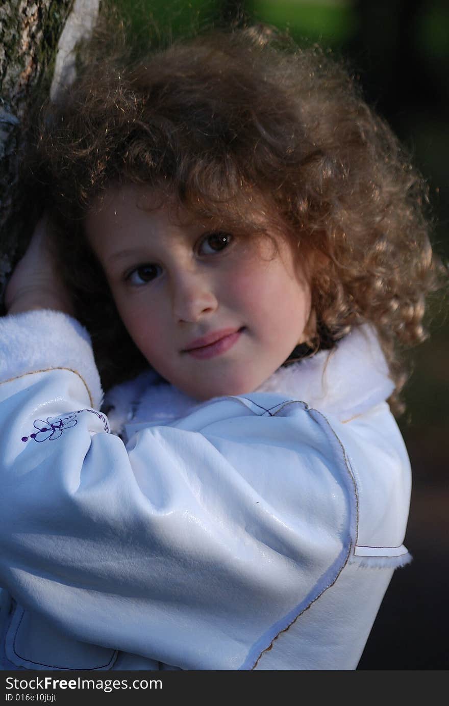 Little girl in a park next to a birch