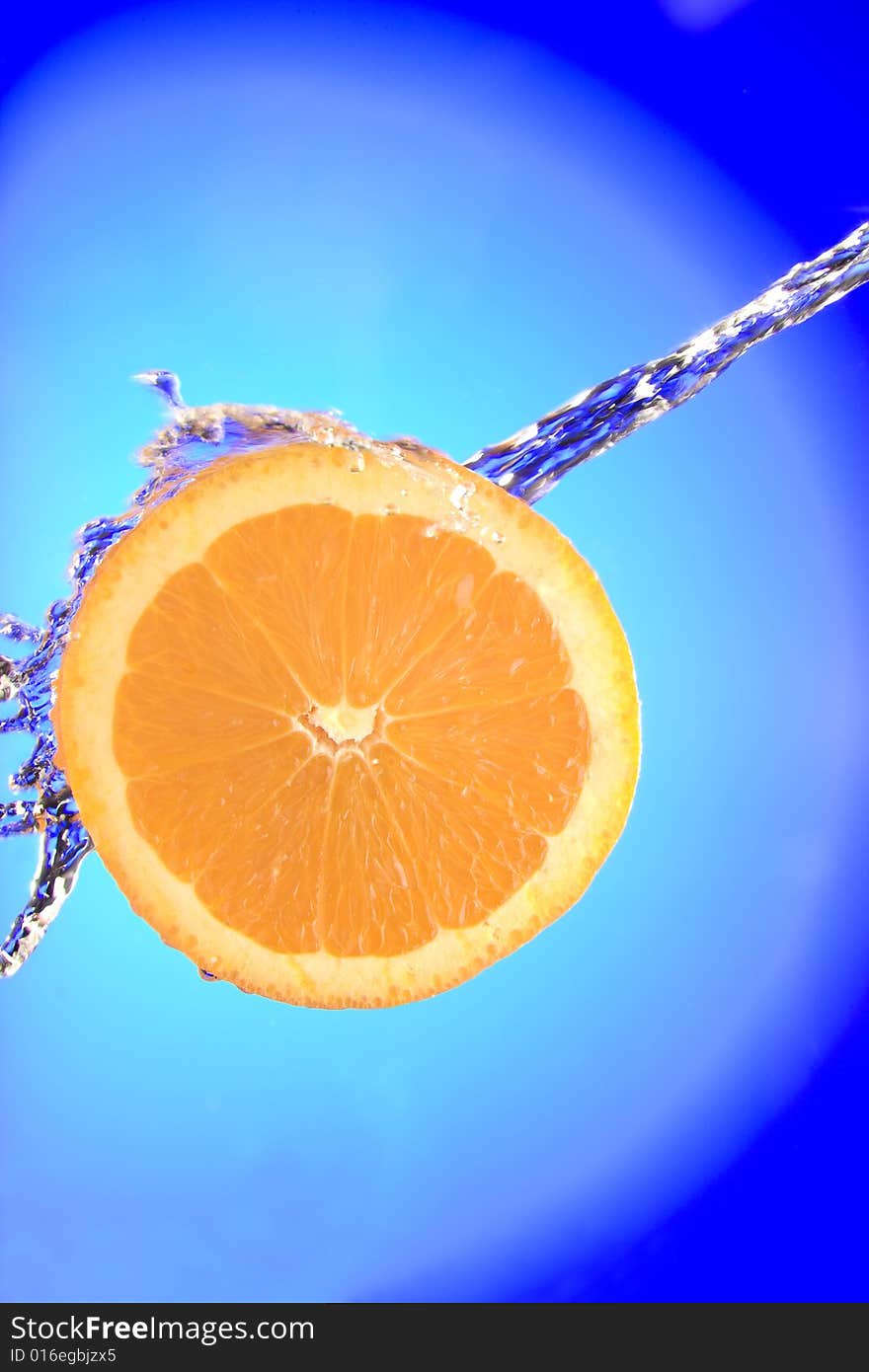 Close up view of sliced orange piece getting splashed with water. Close up view of sliced orange piece getting splashed with water