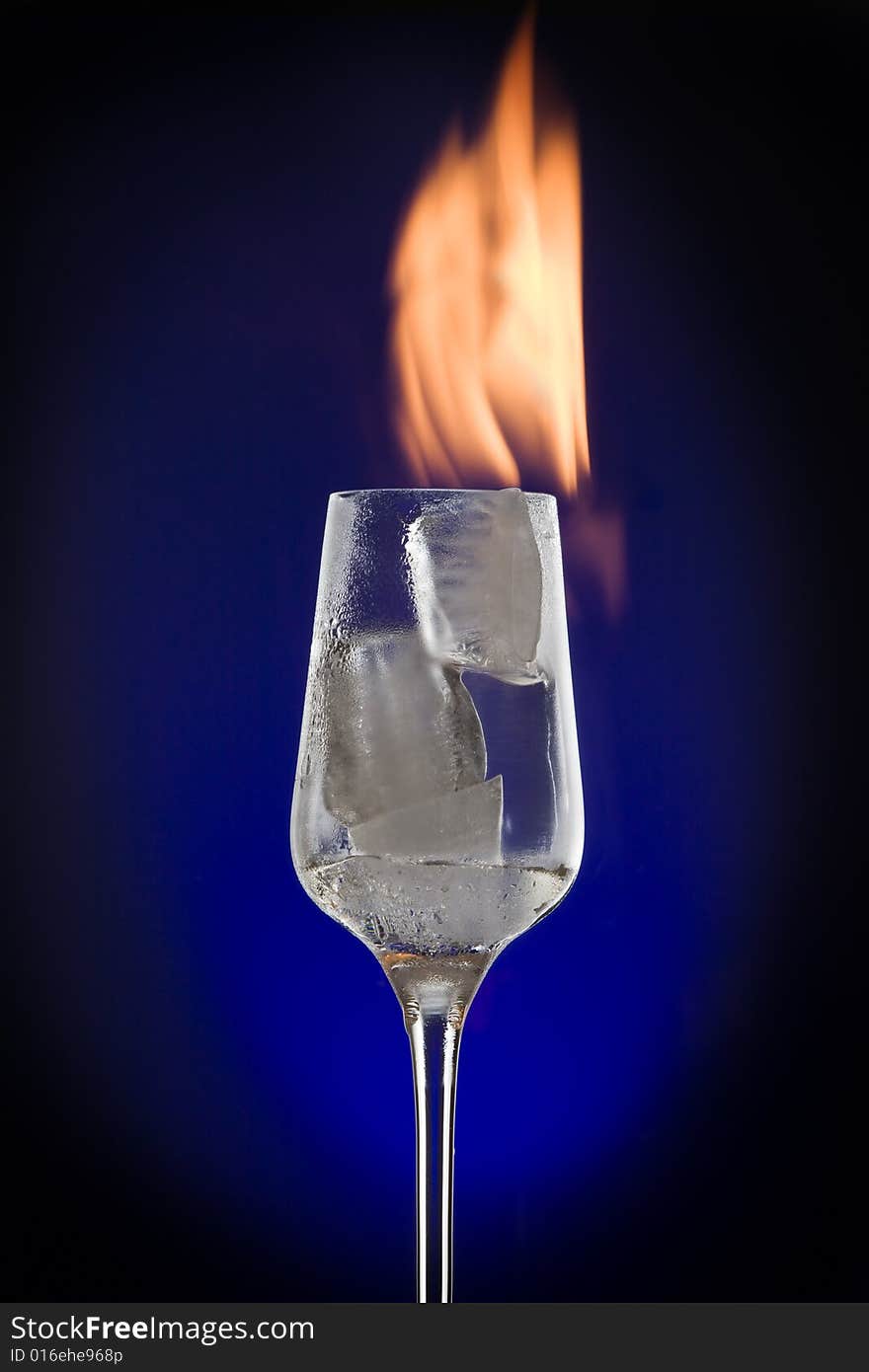 View of cocktail glass filled with burned ice on blue back. View of cocktail glass filled with burned ice on blue back