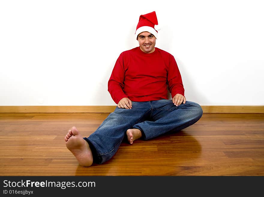 Young man with santa claus hat sitting in the floor