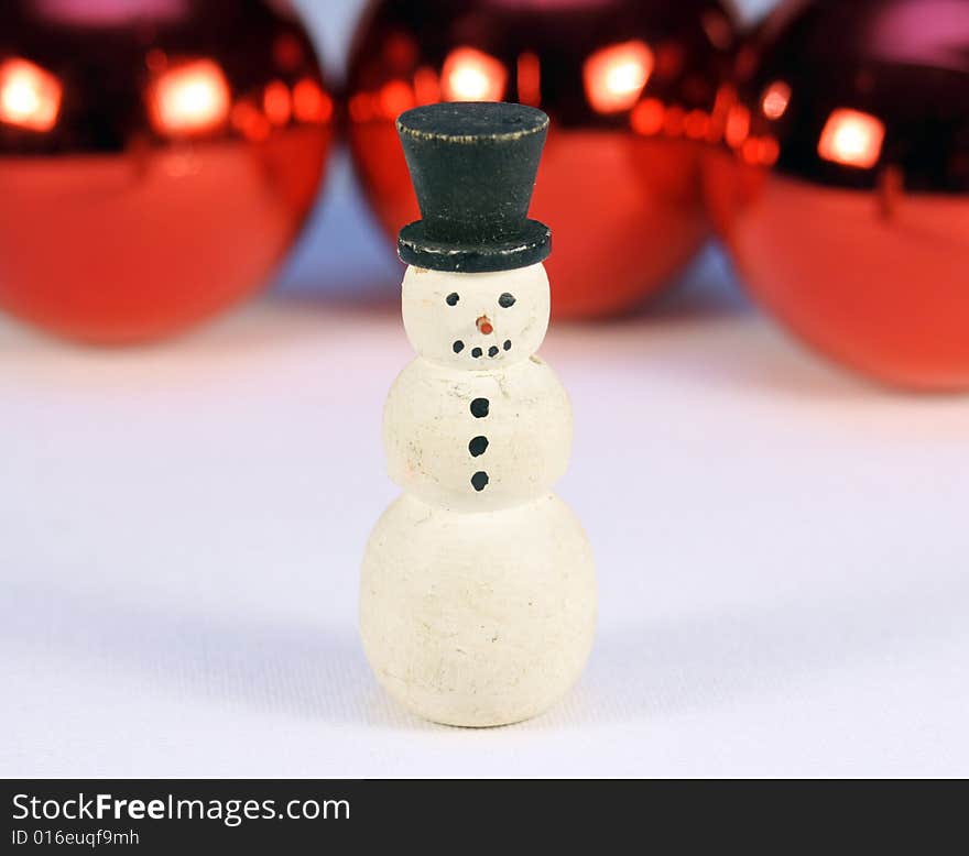 Snow man with shiny red christmas balls behind