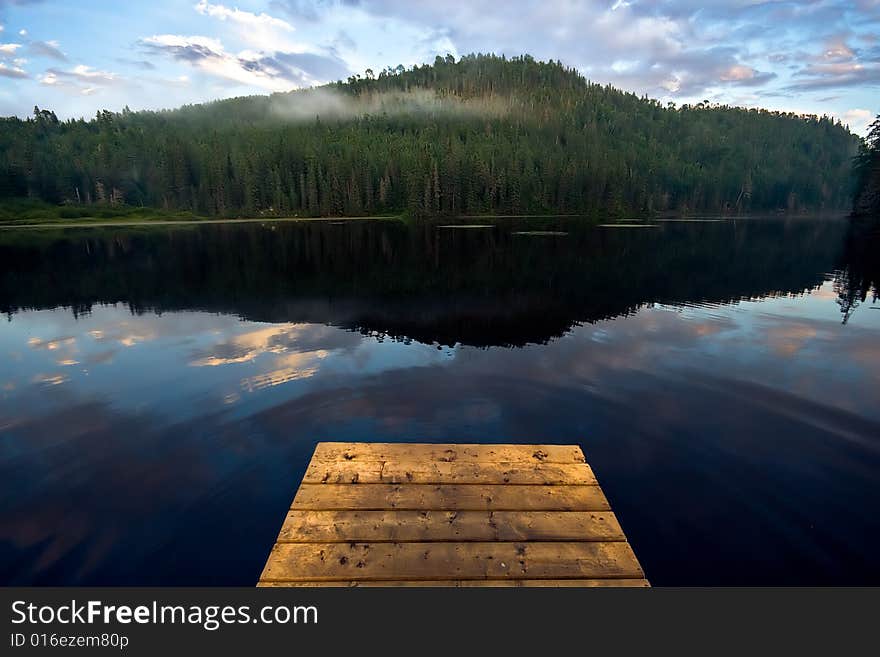 Peaceful fishing lake with deck and a mountain in the background. Peaceful fishing lake with deck and a mountain in the background