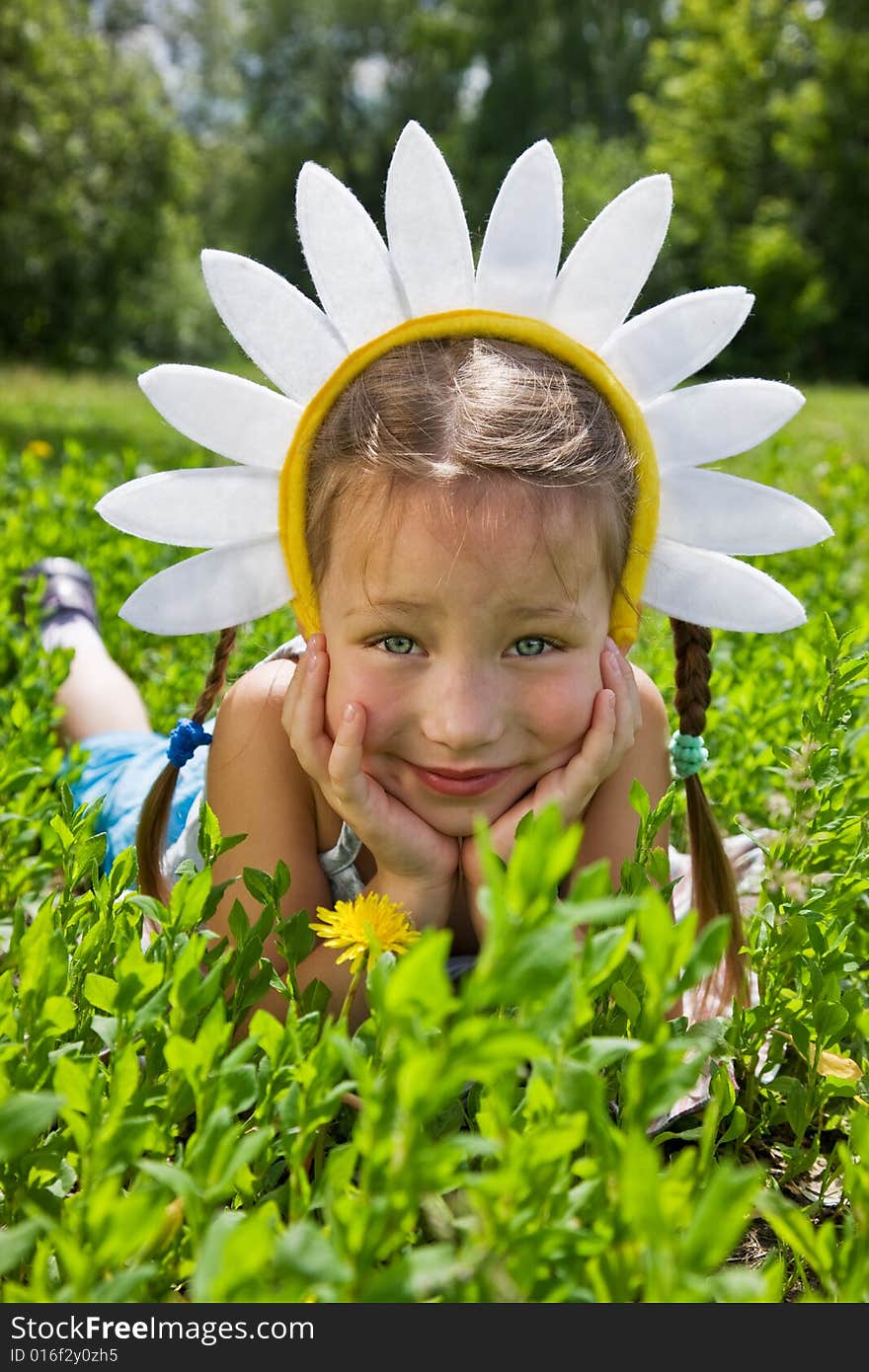 Portrait of little girl in camomile hat on green grass in a sunny day. Portrait of little girl in camomile hat on green grass in a sunny day