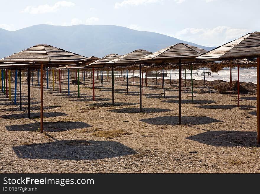 Set of beach umbrellas on sand making shadows under the blue clear sky in hot day