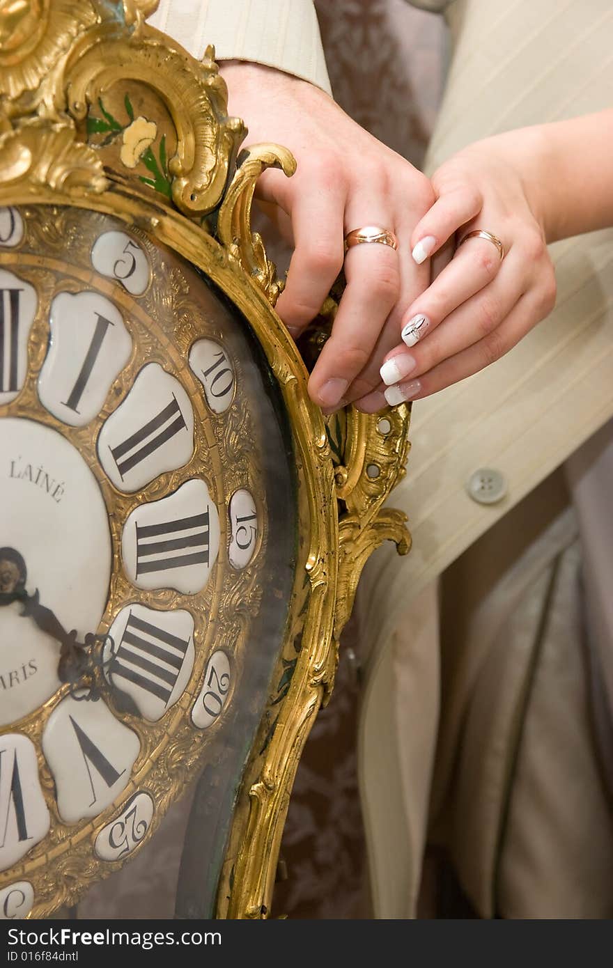 Married couple hands on old clock