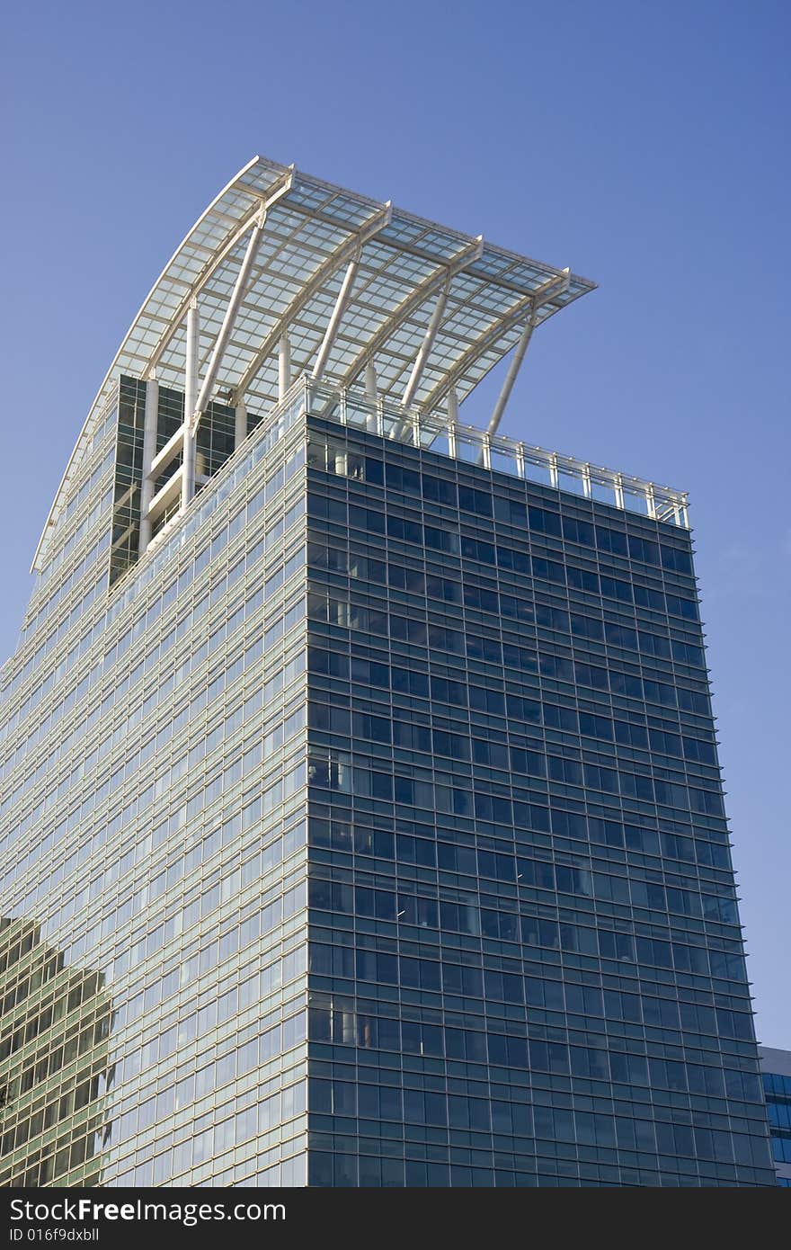 A blue office tower with a curved white roof. A blue office tower with a curved white roof