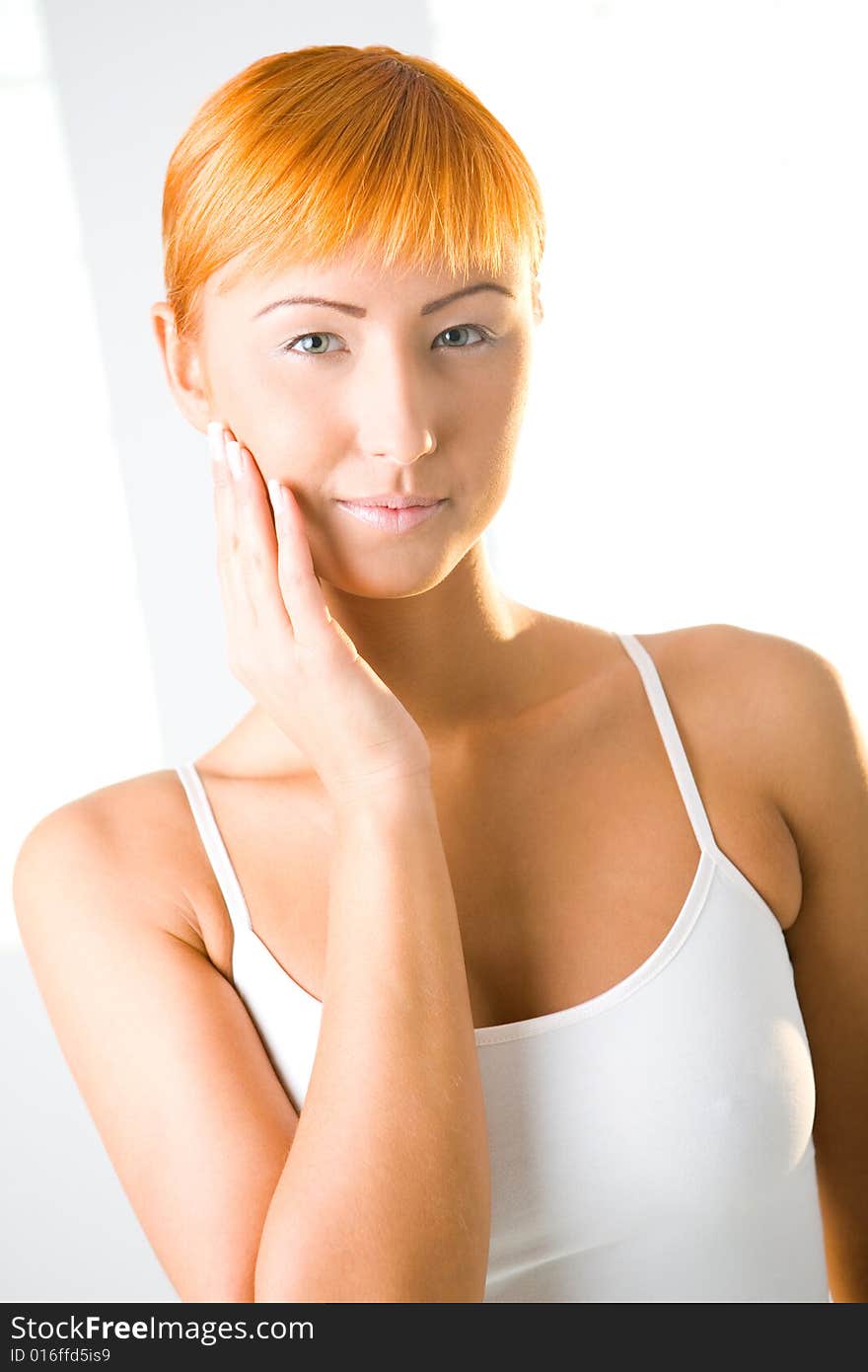 Young red-haired woman touching her skin on face. She's  looking at camera. Front view. Young red-haired woman touching her skin on face. She's  looking at camera. Front view.