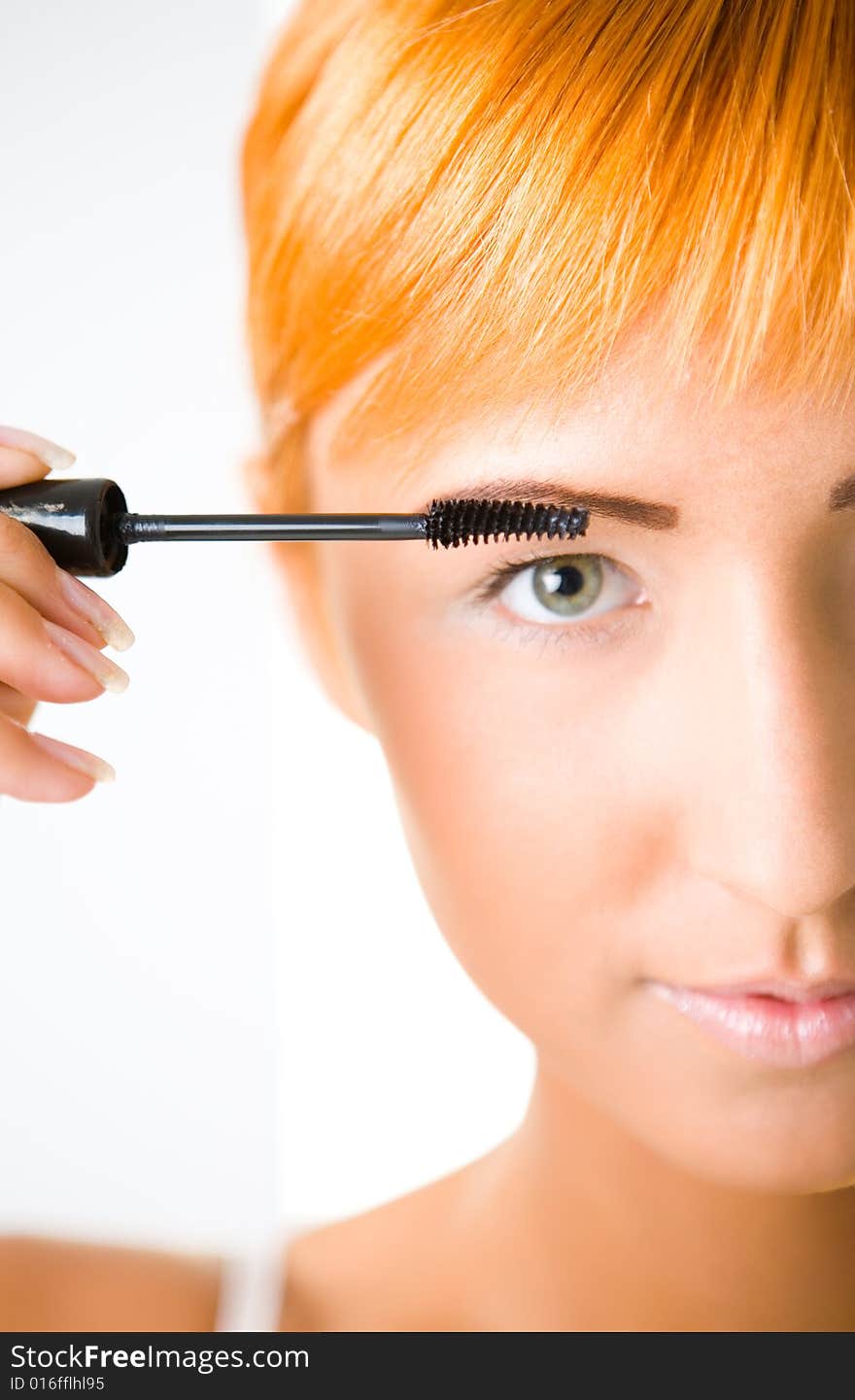 Young woman putting eyelash mascara. She's looking at camera. Closeup on face. Front view. Young woman putting eyelash mascara. She's looking at camera. Closeup on face. Front view.