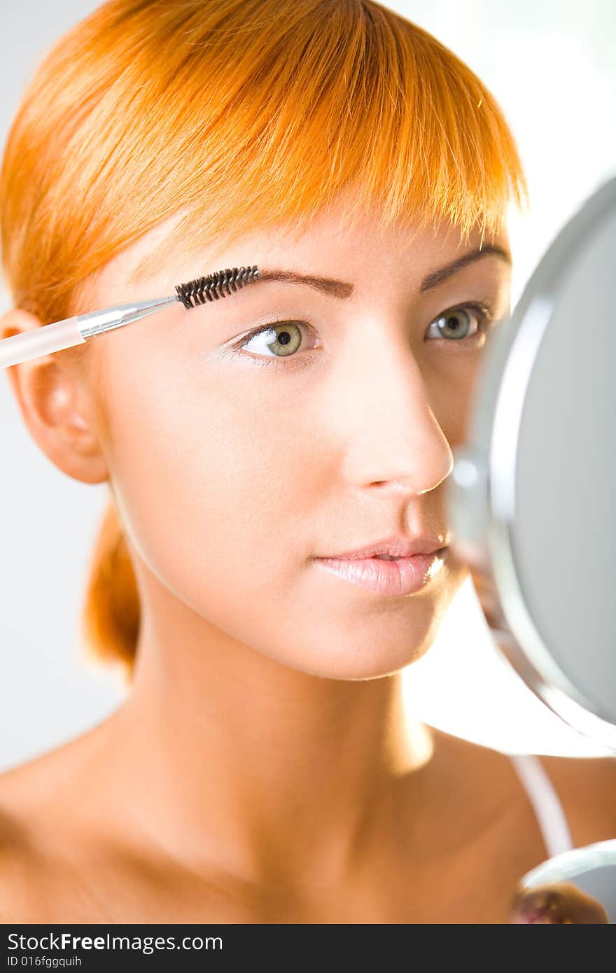 Young woman making her makeup. Front view.