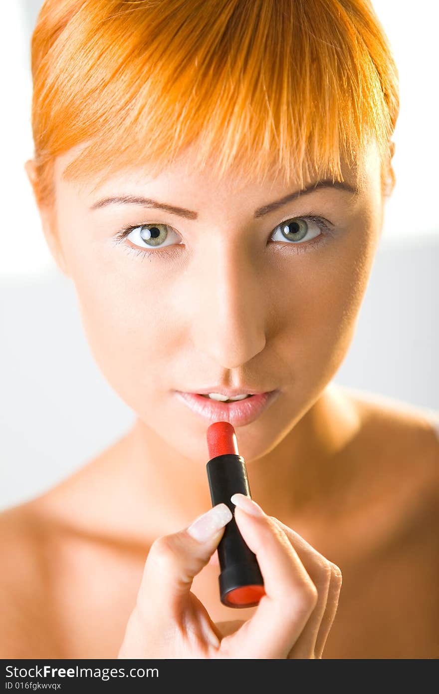 Beautiful woman applying red lipstick. She's looking at camera. Closeup on face. Front view. Beautiful woman applying red lipstick. She's looking at camera. Closeup on face. Front view.