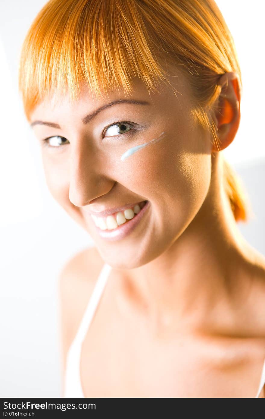 Young woman with cream under eyes. She's looking at camera. Closeup on face. Young woman with cream under eyes. She's looking at camera. Closeup on face.