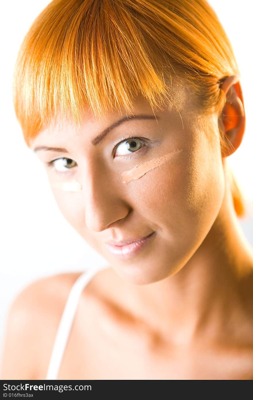 Young woman with cream under eyes. She's looking at camera. Closeup on face. Young woman with cream under eyes. She's looking at camera. Closeup on face.