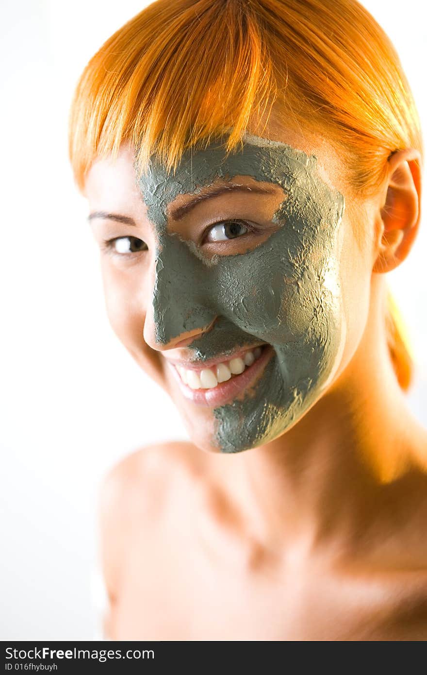 Young red-haired woman with green mask on half face. She's smiling and looking at camera. Closeup on face. Young red-haired woman with green mask on half face. She's smiling and looking at camera. Closeup on face.