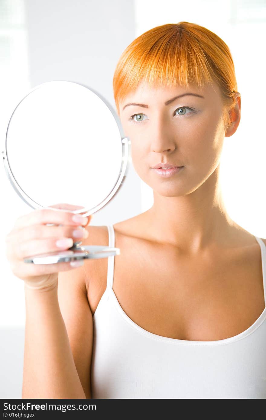 Young woman looking in mirror. Front view. Young woman looking in mirror. Front view.