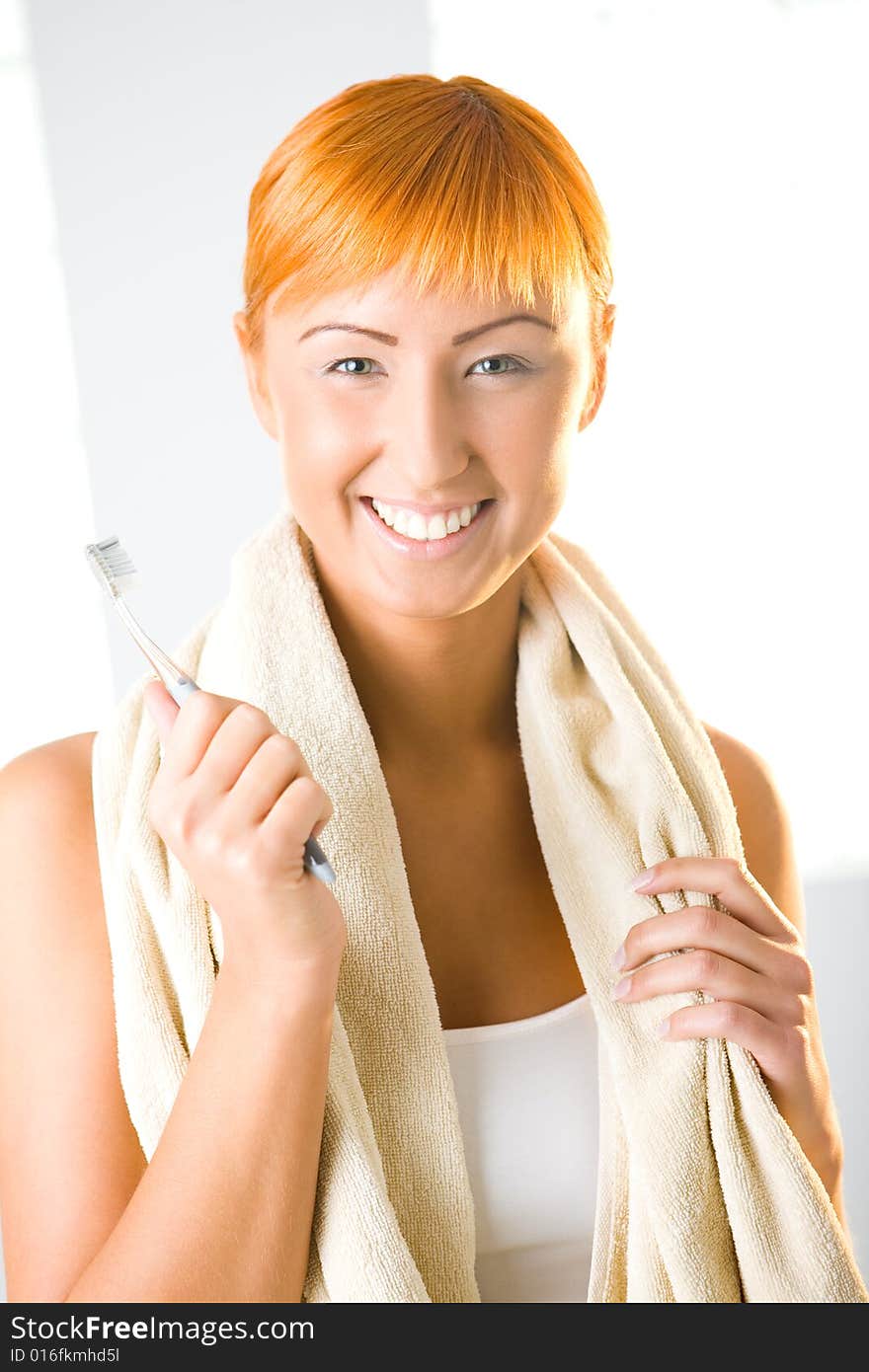 Young beauty woman with toothbrush and towel. She's smiling and looking at camera. Front view. Young beauty woman with toothbrush and towel. She's smiling and looking at camera. Front view.