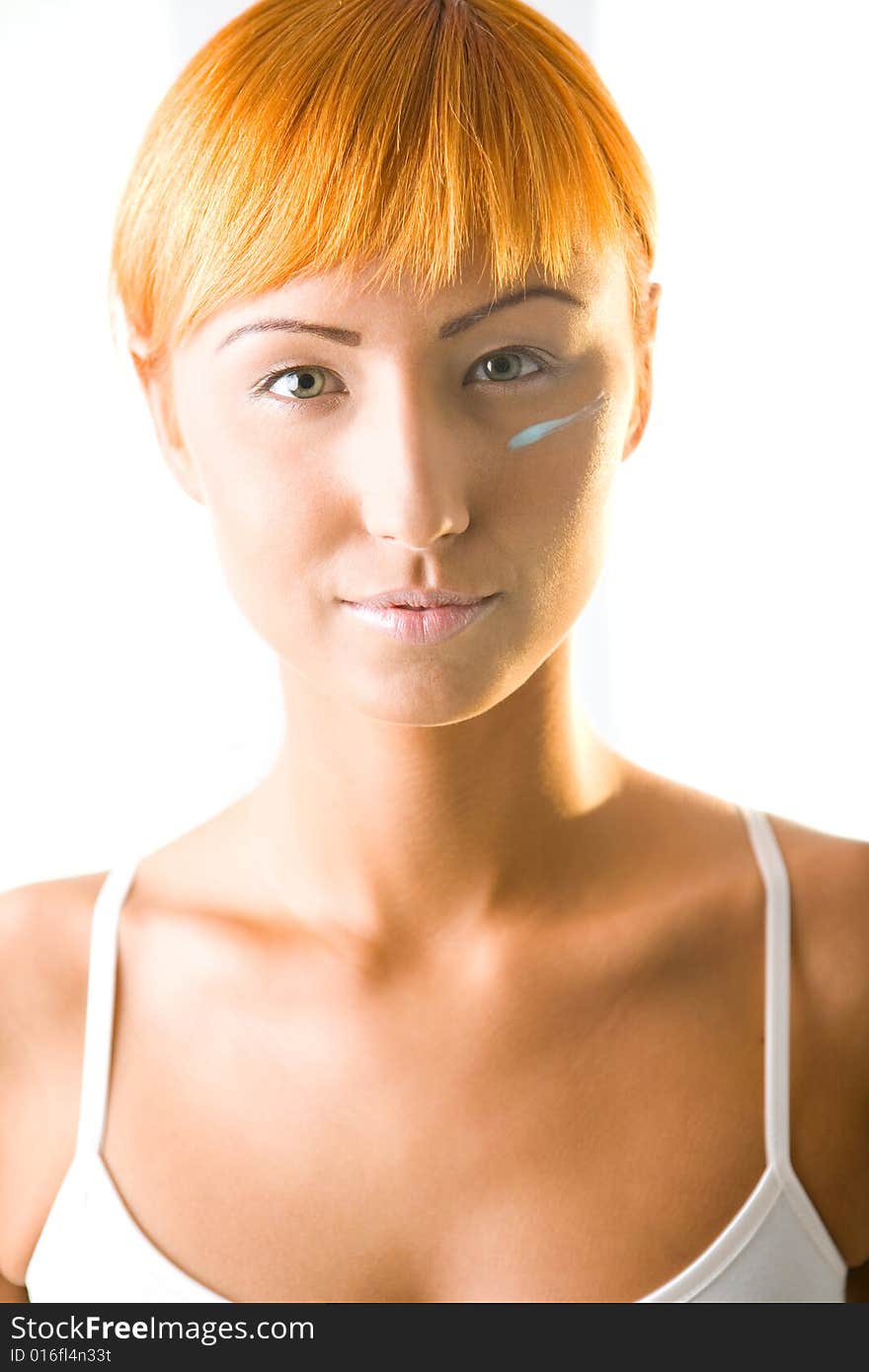 Young woman with cream under eyes. She's looking at camera. Front view. Young woman with cream under eyes. She's looking at camera. Front view.