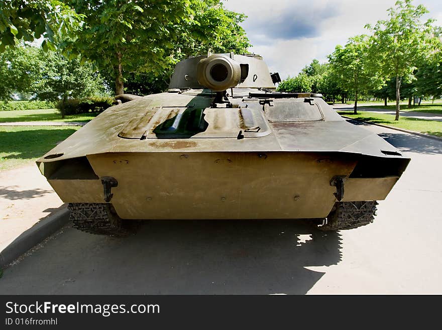 A front view of an old tank parked in a park. A front view of an old tank parked in a park