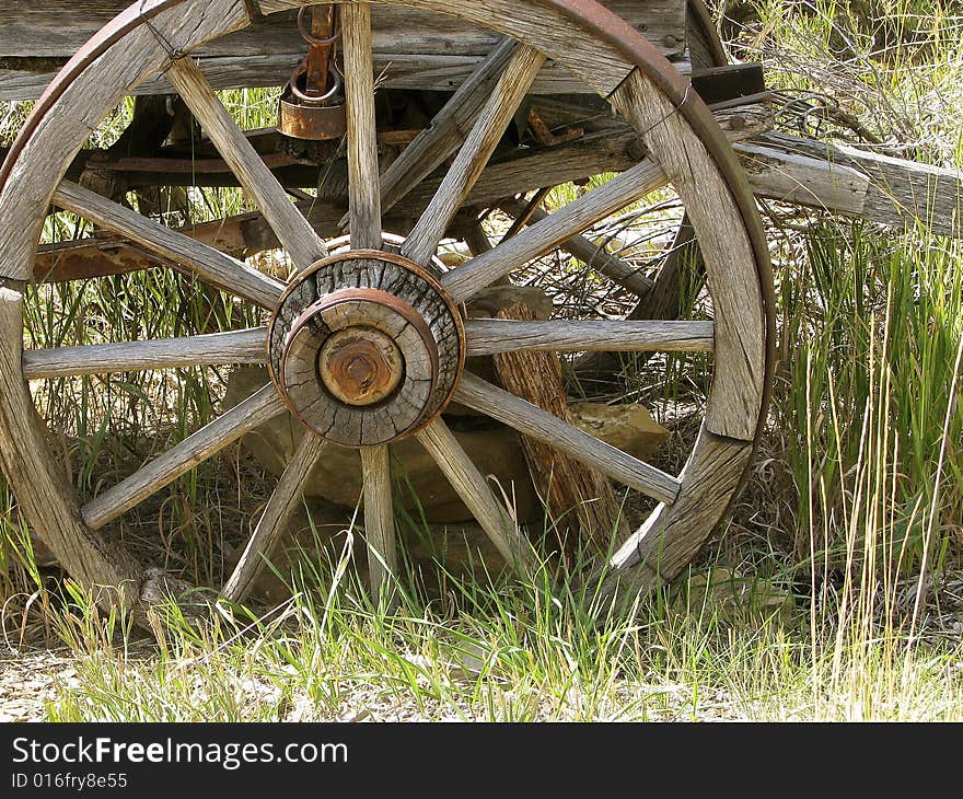 Really old worn wagon wheel in grass. Really old worn wagon wheel in grass