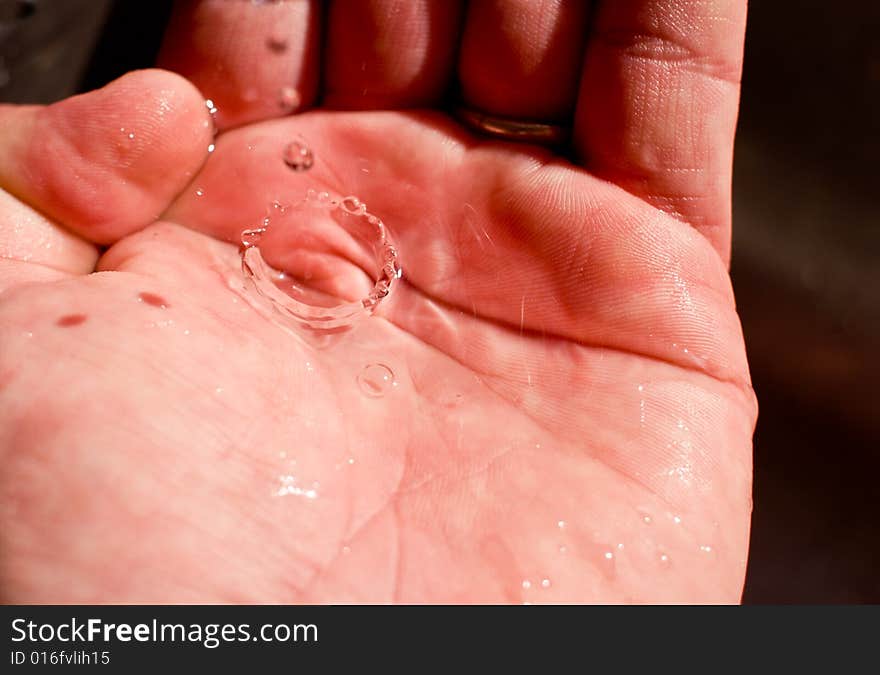 A water drop is caught in the hand. Clean drinking water is a precious resource. A water drop is caught in the hand. Clean drinking water is a precious resource.