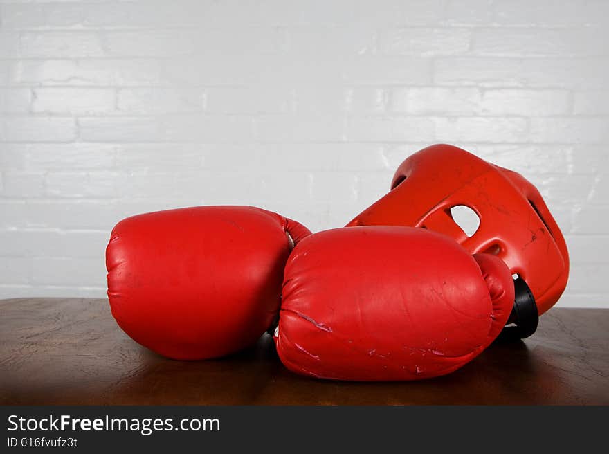 A pair of worn boxing gloves and head gear on a workout bench. A pair of worn boxing gloves and head gear on a workout bench