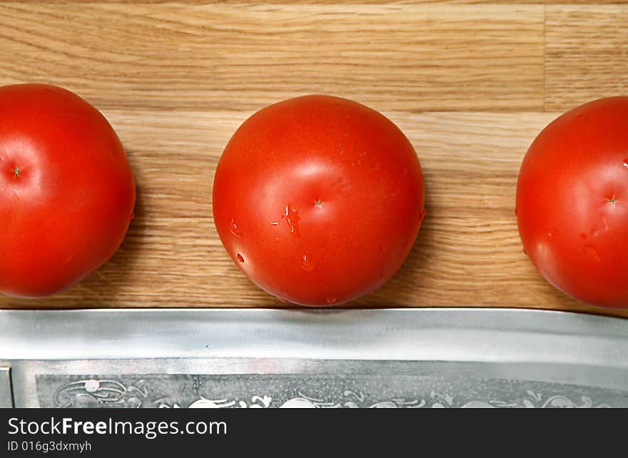 Sharp knife and tomato on a bamboo chopping board