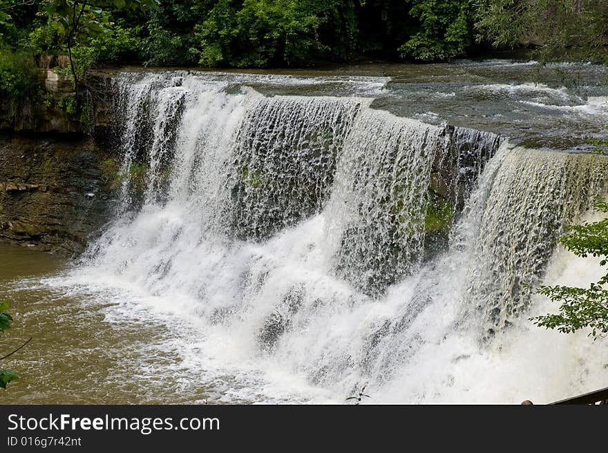 Water falling quickly over rocks surrounded by tons of green trees and plants. Water falling quickly over rocks surrounded by tons of green trees and plants