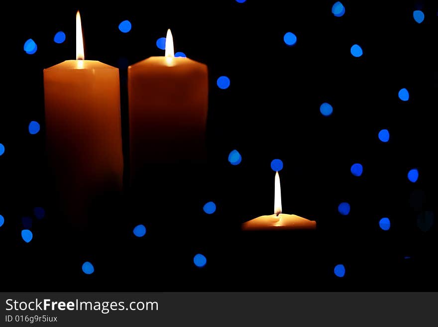 Three large candles lit amongst blue lights