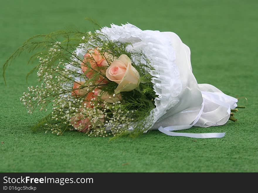 The beautiful wedding bouquet of roses lays on a grass.