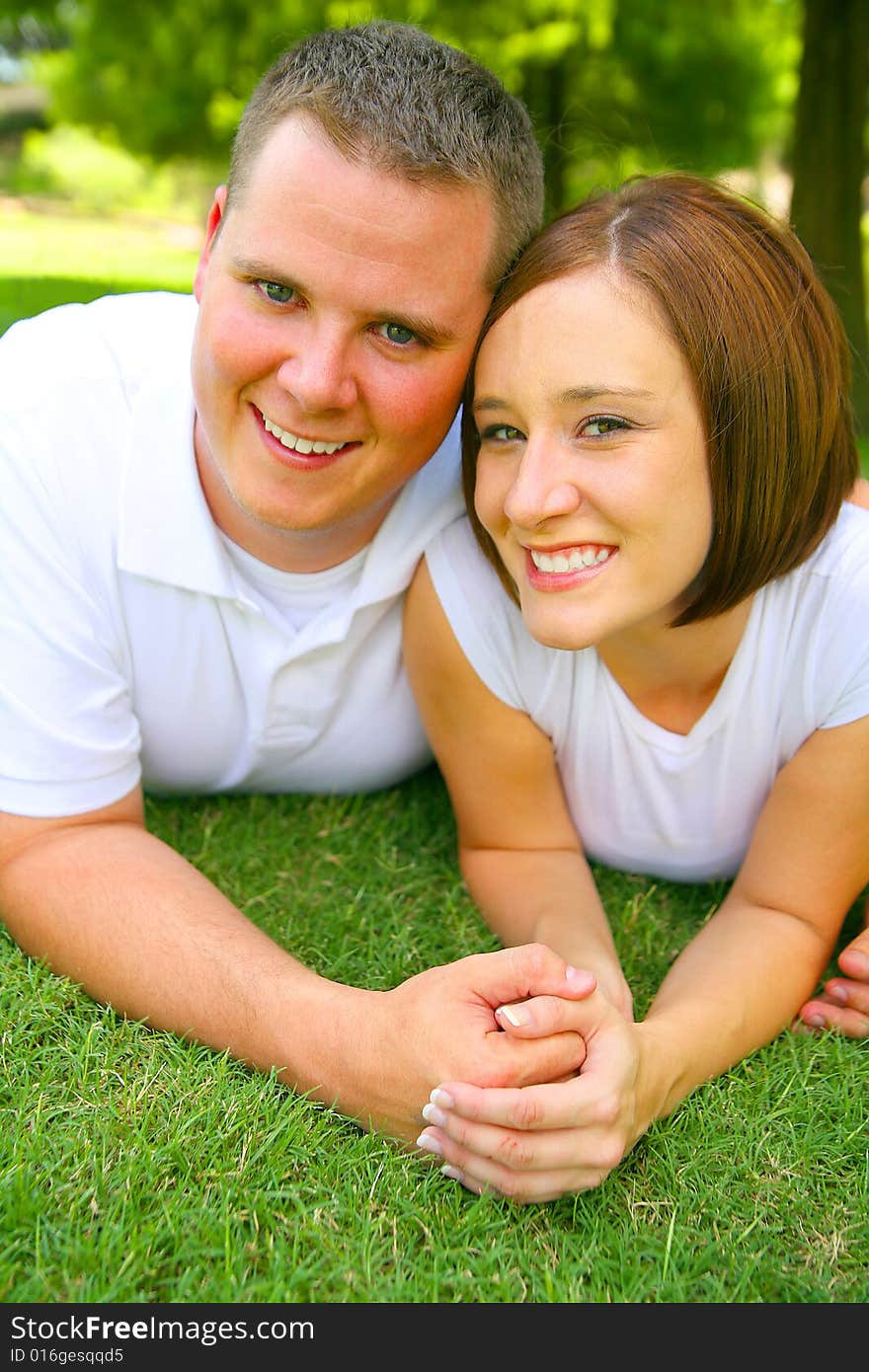 Happy caucasian couple laying on grass and holding hand with smile. concept for happiness and family. Happy caucasian couple laying on grass and holding hand with smile. concept for happiness and family