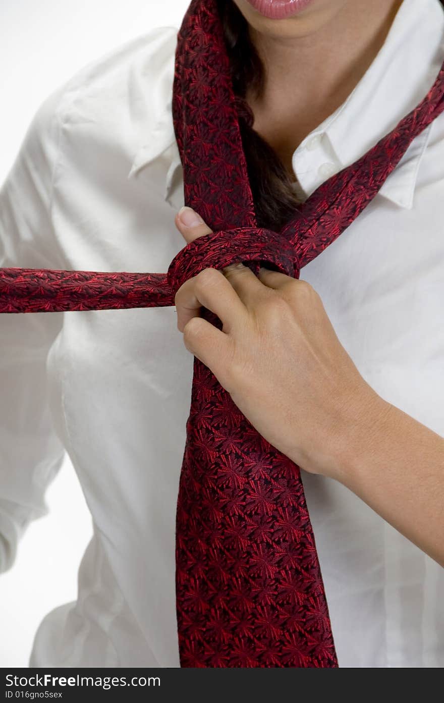 Young pretty woman tying her tie against white background