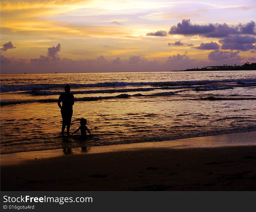 Silhouette of a woman taking care of her daughter at a sunset beach holiday. Silhouette of a woman taking care of her daughter at a sunset beach holiday