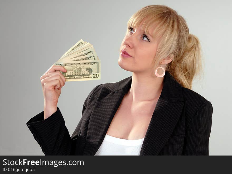 Woman fans herself with American currency on grey background