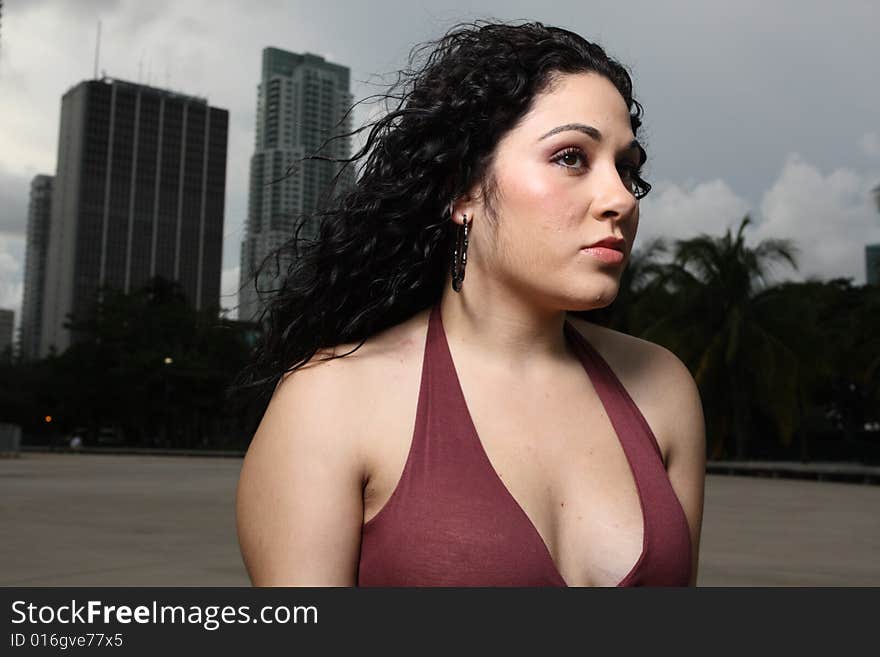 Young depressed female in a revealing dress standing outside with buildings in the background. Young depressed female in a revealing dress standing outside with buildings in the background.