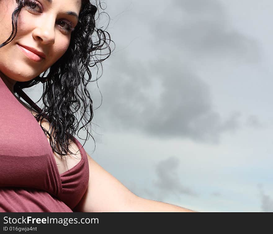 Woman smiling with a dark and cloudy sky in the background. Woman smiling with a dark and cloudy sky in the background.