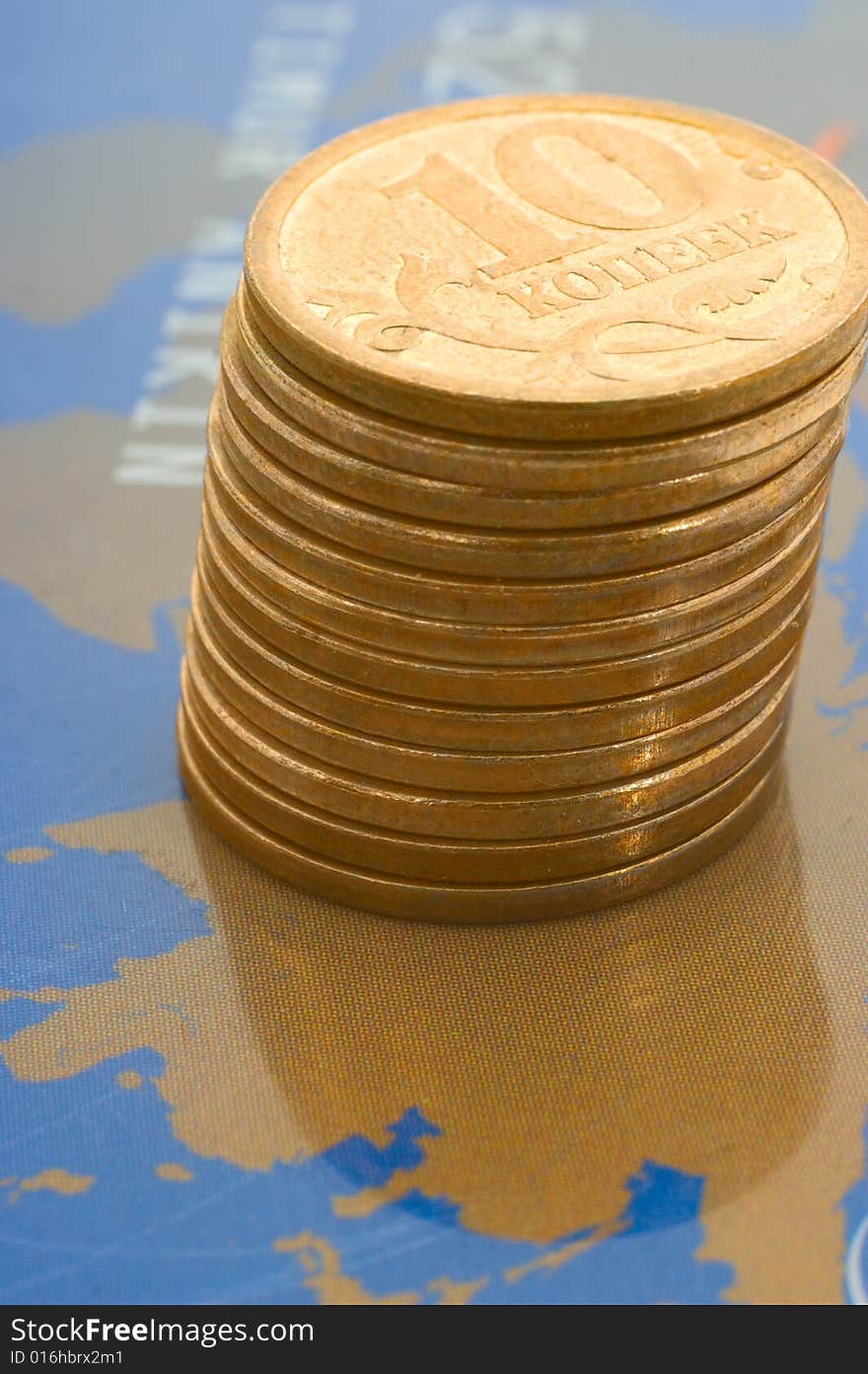 Stack of shiny coins over world map on plastic card. Stack of shiny coins over world map on plastic card