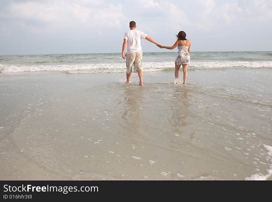 Couple walking at the beach holding hands in the ocean