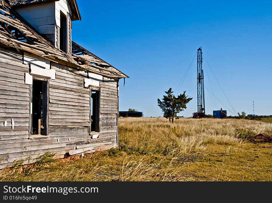 Abandoned house on the left and a drilling rig drilling for oil on the right with a cedar tree between the two. Legend has it that a cedar tree stands between life and death. Abandoned house on the left and a drilling rig drilling for oil on the right with a cedar tree between the two. Legend has it that a cedar tree stands between life and death.