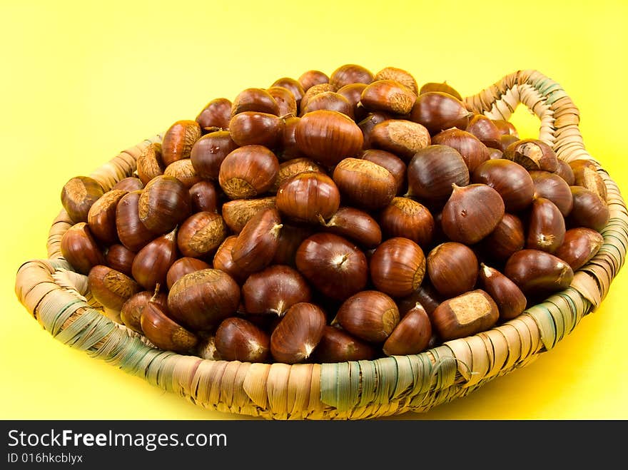 Many ripe chestnuts on yellow background