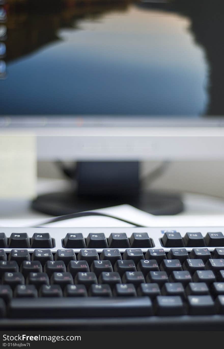 Shallow depth of field on a computer keyboard. On the background can be seen a part of the desktop LCD monitor. The focus is on the keyboard buttons.