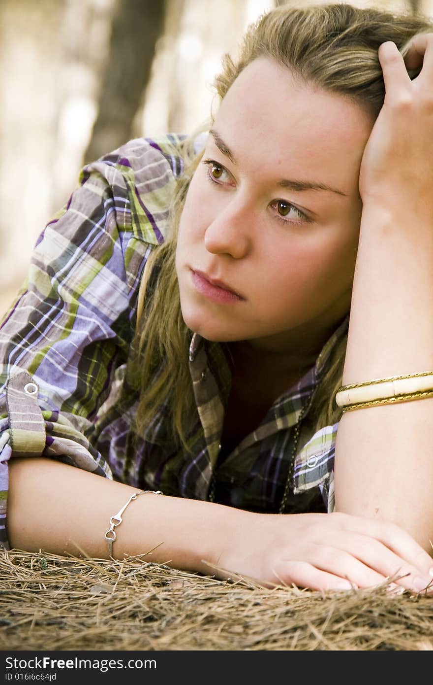 Young laying pensive woman over dead pine tree leaves. Young laying pensive woman over dead pine tree leaves.