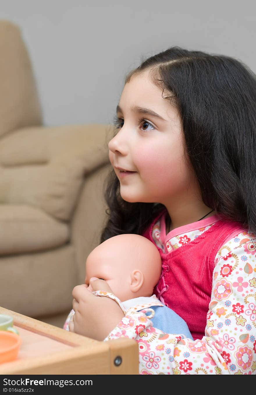 Adorable little brunette girl playing with doll. Adorable little brunette girl playing with doll