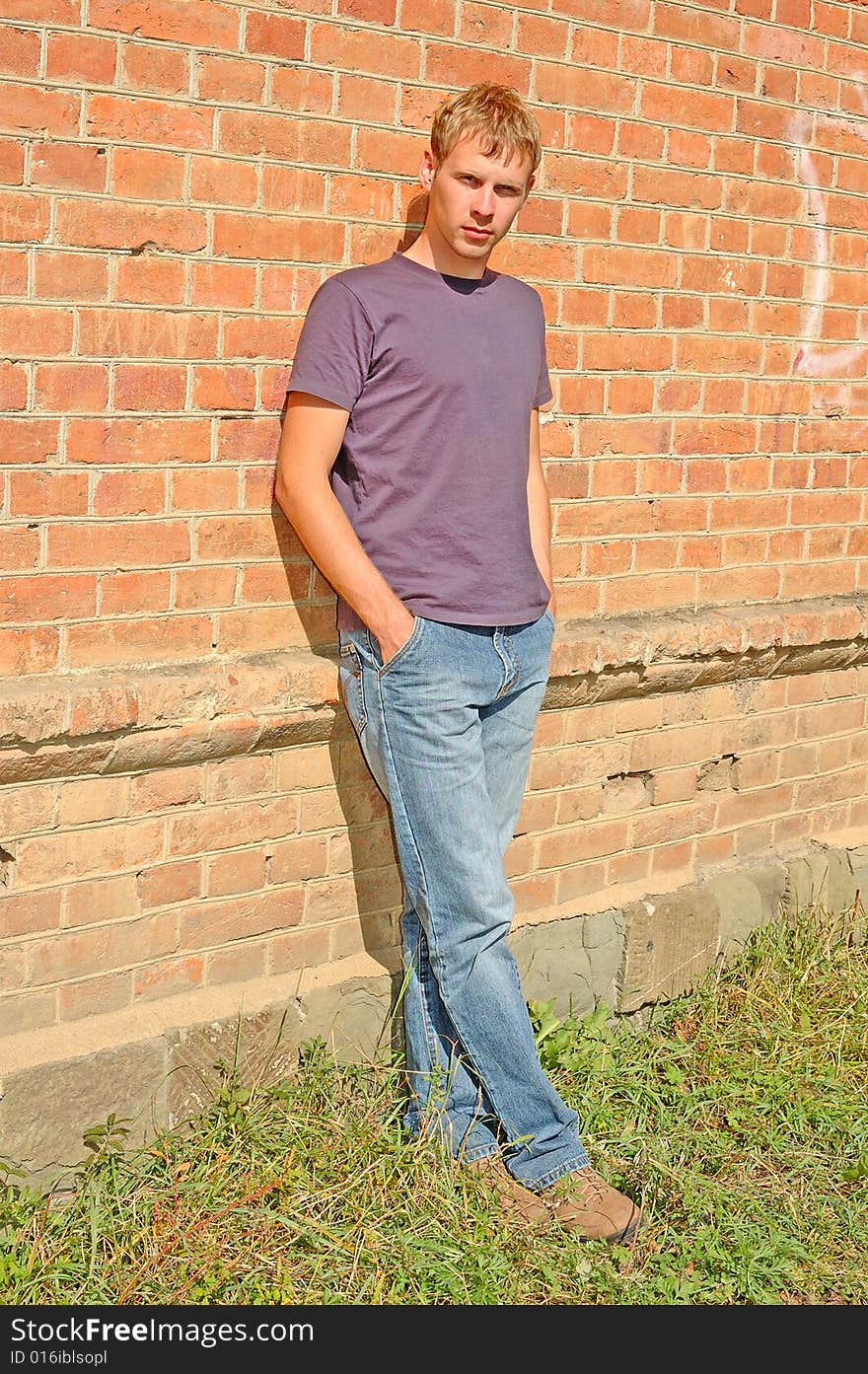 Young stylish man with blonde hair stand near brick wall. Young stylish man with blonde hair stand near brick wall.