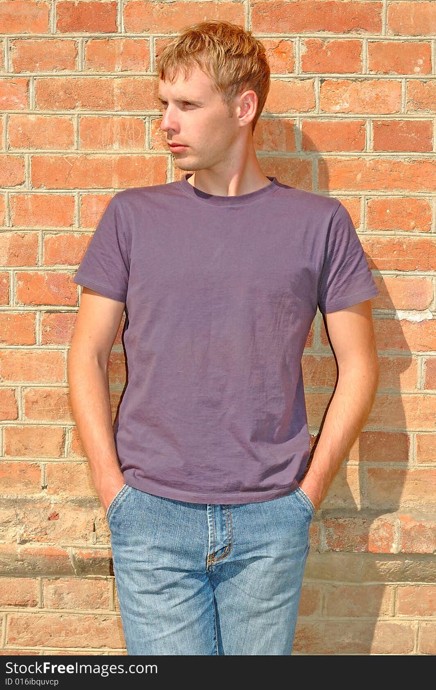 Young stylish man with blonde hair stand near brick wall. Young stylish man with blonde hair stand near brick wall.