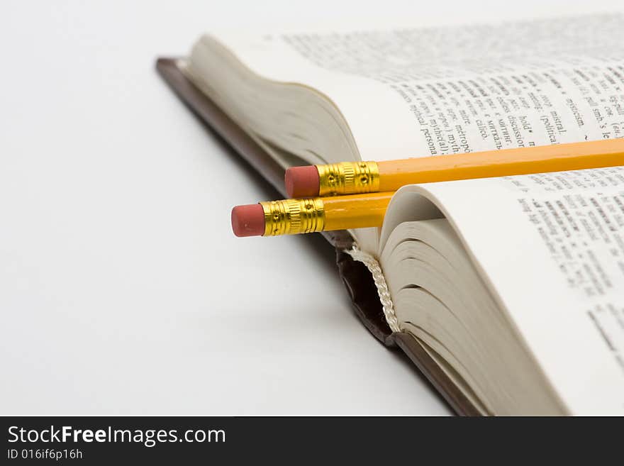 Book with pencils on white background