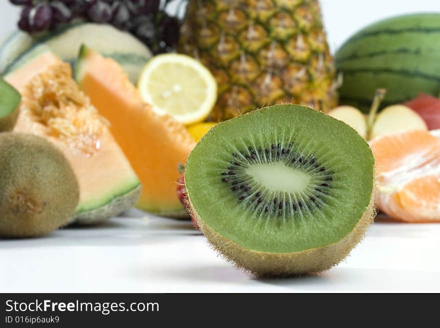 A beutiful sliced fresh kiwi on a backround of a heap of tropical fruits