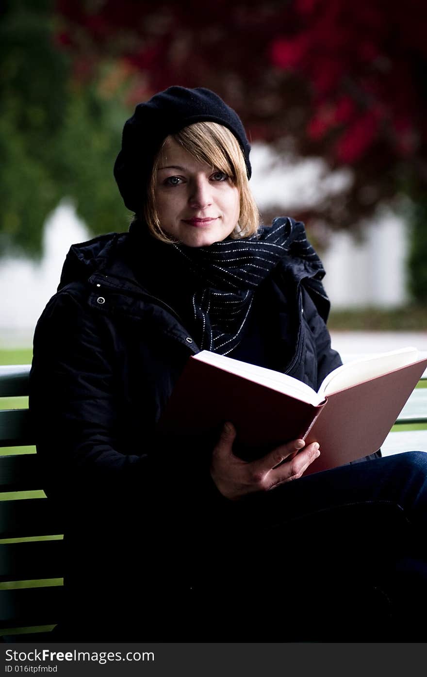 Girl reading a book outside on a park bench. Girl reading a book outside on a park bench