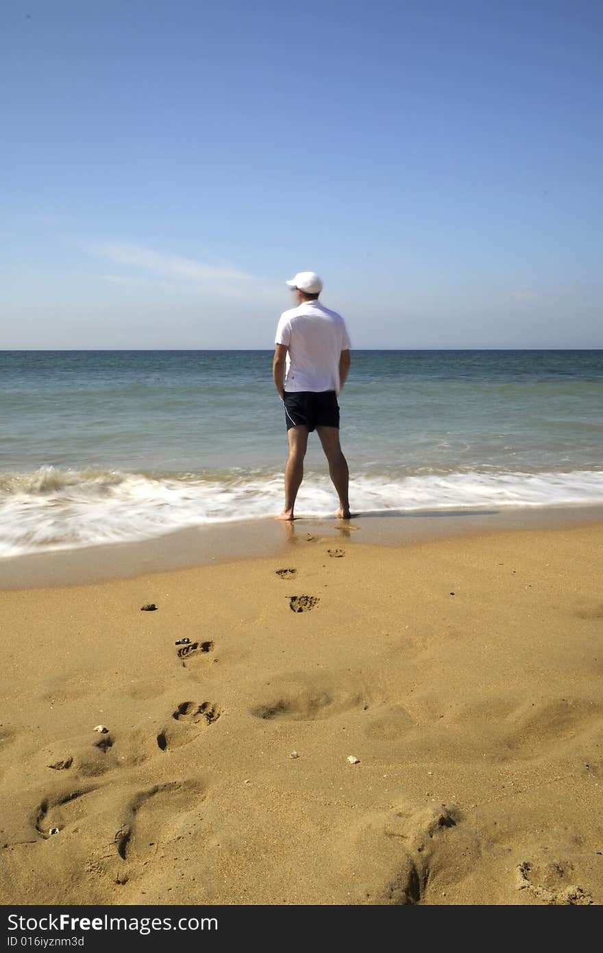 Man in white shirt watchig the ocean. Man in white shirt watchig the ocean