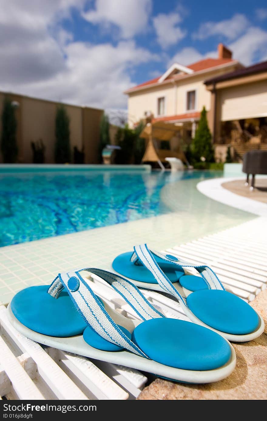 Two blue slippers near swimming pool in hotel